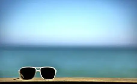 A pair of sunglasses on a wooden deck overlooking the ocean.