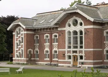 A large red brick building with a lawn in front of it.