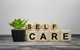 Wooden blocks spelling "Self Care" with a plant.